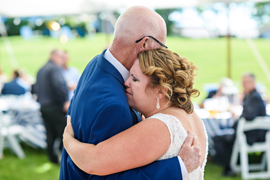 A bride crying while dancing with her father at her wedding.